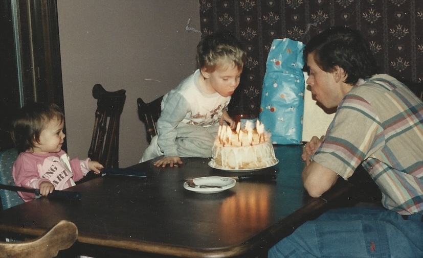 Henry and his son blowing out candles on a birthday cake when he was younger